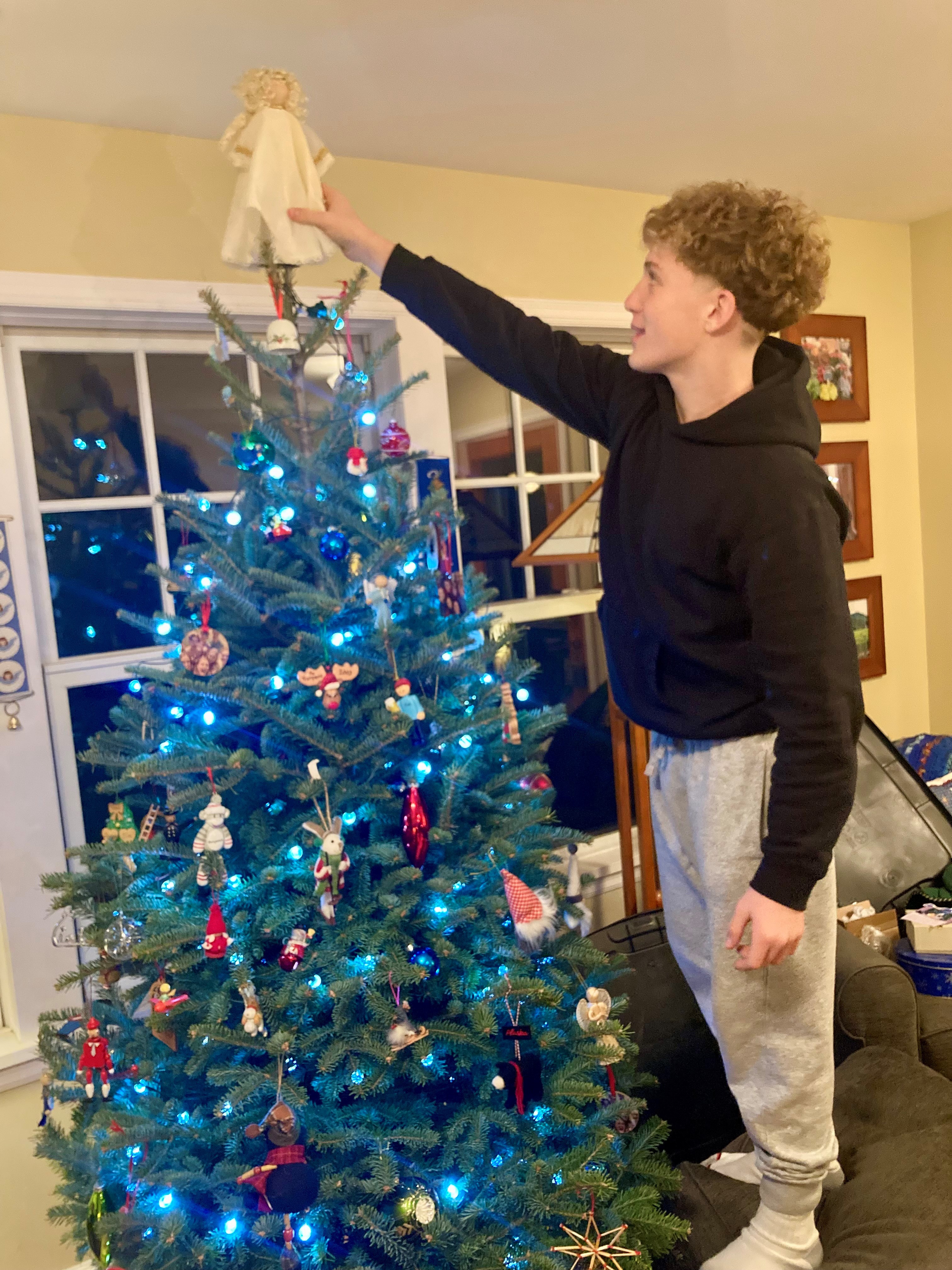 Guille placing the angel on top of the tree